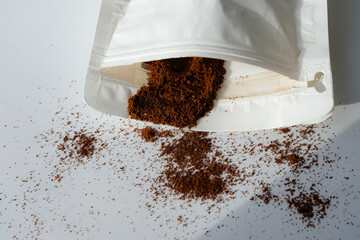 Ground coffee in a white coffee bag with a valve and zipper. Sunlight. Copy space.