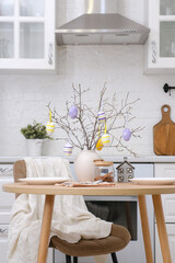Home spring easter design in kitchen. Ceramic vase with spring branches with easter eggs, plates...