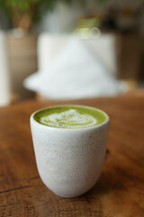 Top view of matcha green tea latte with a latte heart art on wooden table cafe background