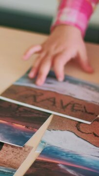 Vertical video. Photo collection. Travel pictures. Child leisure. Little kid hands moving journey memories sea trip images collage on table.