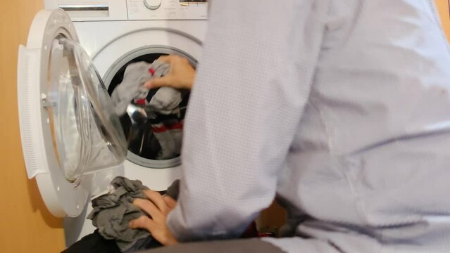 A person loading dirty clothes. Promoting gender equality, shared responsibility, and teamwork in household chores, reflecting the commitment of both men and women to family well-being.