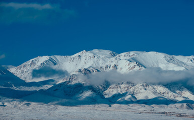 Snow covered mountain peaks with clouds in winter