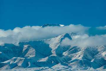 Fototapeta na wymiar Snow covered mountain peaks with clouds in winter
