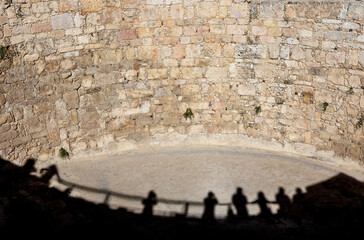 Shadows of tourists leaning on the railing of an ancient Roman stone water tank in  the Amman Citadel . Amman in Jordan. 