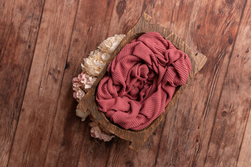 Bowl for a photo shoot of a newborn baby. Bowl with crimson background.Badeck on a wooden floor.