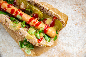 Hot Dog takeaway food sausage bun, tomato sauce, pickled cucumber, green lettuce leaf  tasty fresh eating meal food snack on the table copy space food background rustic top view