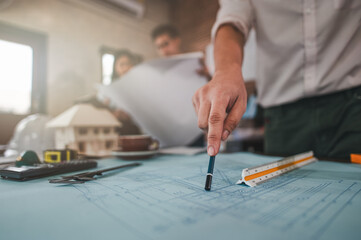 architecture, architect, construction, engineer, project, design, blueprint, house, model, plan. architects, engineer holding pen pointing equipment architects on the desk with a blueprint in office.
