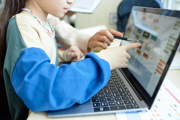 Close up of young schoolgirl pointing at computer screen while working on online assignmentwith copy space