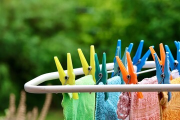 Wäsche hängt an Wäscheständer, Kleidung wird mit Wäscheklammern im Garten aufgehängt, Hausarbeit erledigen