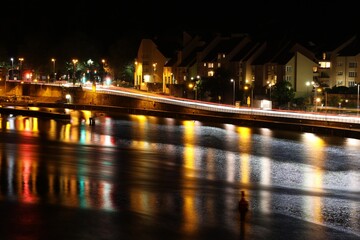 View on a street and the river Neckar in Heidelberg, Germany at night with colorful lights reflected by the surface of the water