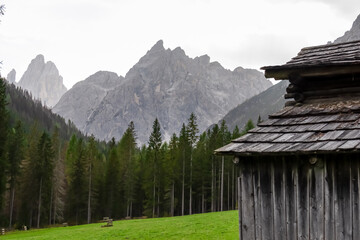 Fototapeta na wymiar Wooden hut on alpine meadow with scenic view of majestic rugged mountain peaks of Sexten Dolomites, South Tyrol, Italy, Europe. Hiking in panoramic Fischleintal, Italian Alps. Idyllic conifer forest