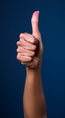 Hand giving a thumbs up gesture against a blue background