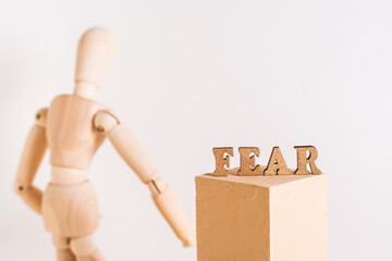 The word fear and a wooden sad man stands with his back