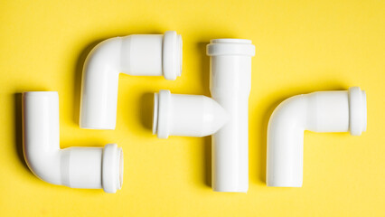 White sewage fittings lying on a colorful bright yellow background