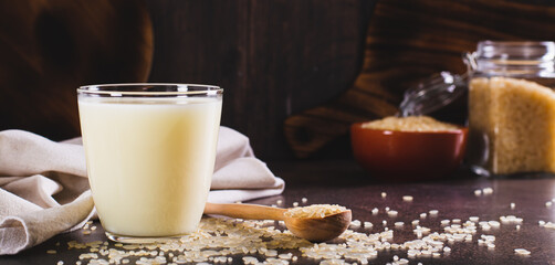 Lactose-free rice milk in a glass and rice cereal on the table web banner