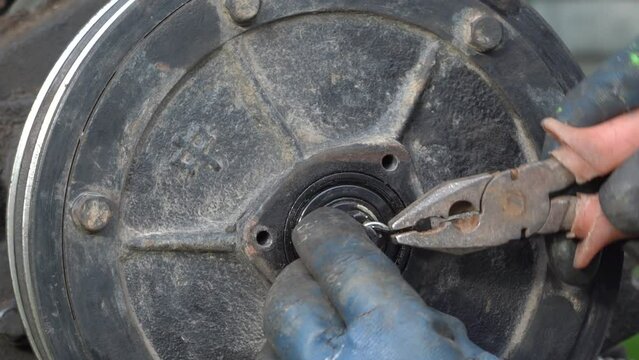Mechanic removing cotter pin safety wire of nut lock , the mechanic uses pliers to remove the cotter pin from the nut in the tractor, repairing the clutch of the walk-behind tractor