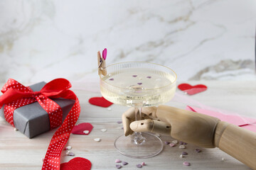 Background or greeting card for Valentine's Day. wooden hand holding a glass of heart inside a glass of champagne.