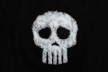 Skull symbol made with rock salt grain, on black background, salt consumption danger metaphor...
