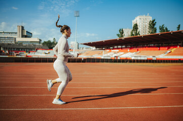 Woman athlete running on a race track in a sports arena