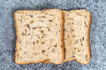 Slice of fresh toast bread with seeds on dark background. Top view overhead with french toast.