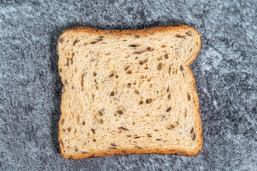 Slice of fresh toast bread with seeds on dark background. Top view overhead with french toast.