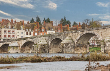 Fototapeta premium Looking across a river at a ancient bridge and town