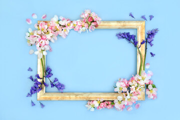 Bluebells and apple blossom flowers spring, Beltane background gold frame on blue. Floral, nature, seasonal abstract border composition.