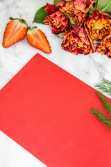 Czerwona kartka ułożona na stole i czerwone róże. © Katarzyna