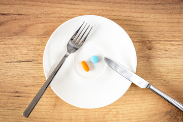 Abuse of medicines, Health concept, Eating medicines with knife and fork from a plate, eating different kinds of pills every day, Abuse of medicines and dietary supplements