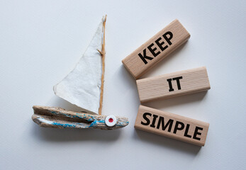 Keep it Simple symbol. Concept words Keep it Simple on wooden blocks. Beautiful white background with boat. Business and Keep it Simple concept. Copy space.