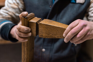 The carpenter glues the details of the cabinet leg