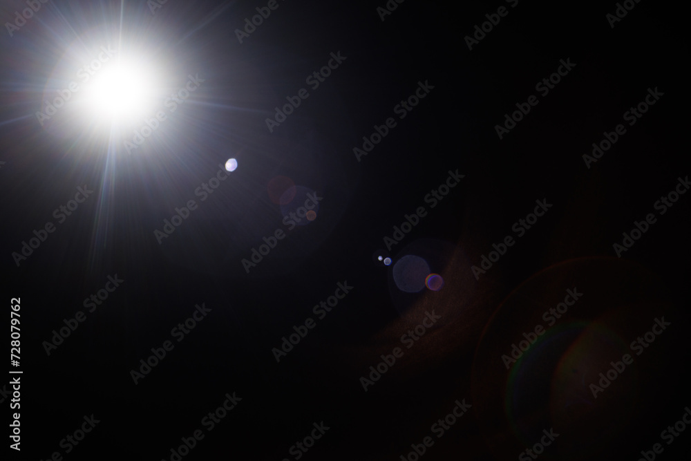 Poster Easy to add lens flare effects for overlay designs or screen blending mode to make high-quality images. Abstract sun burst, digital flare, iridescent glare over black background.