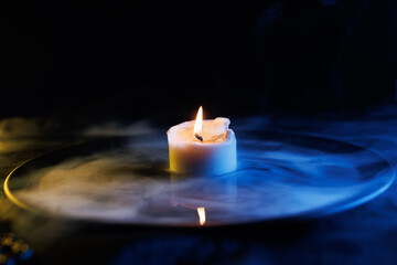 Candle in a bowl with a magical liquid. Colored smoke moves beautifully against on a dark...