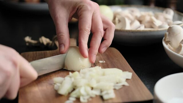 Cutting onions. Woman's hands are cutting onions on the wooden cutting board in the kitchen