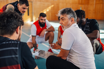 An old basketball trainer is coaching interracial basketball team.