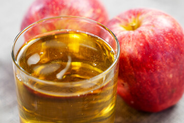 Apple cider in glass on a table with ripe juicy red apples