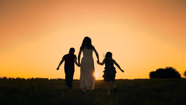 silhouette mother runs into sunset holding her son daughter hand, happy family running, boy girl, fun family activities active kids, dreams brought up, interest life, stage memory friendly relations