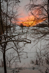 Winter landscape, with trees and hill covered by snow and warm, orange sunset sky - 728090192