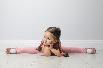 Cute little girl on floor near light grey wall