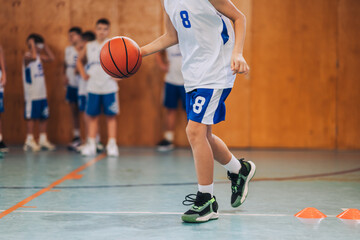 Cropped picture of a junior basketball player dribbling a ball on court.