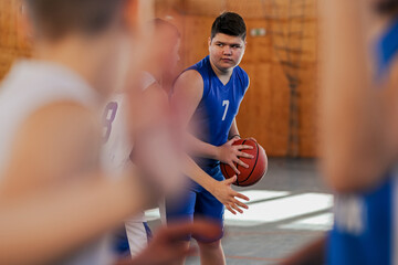 A junior basketball player is guarding a ball during training with team. - obrazy, fototapety, plakaty