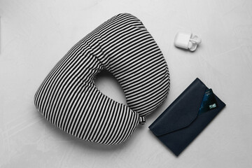 Striped travel pillow, wallet with credit card and earphones on gray background, flat lay