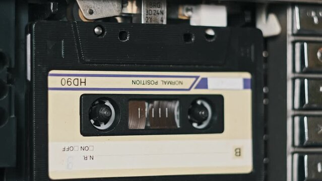 Audio tape recorder playback. Playing an old audio cassette close-up. Vintage record sound in a retro player. Nostalgic tape reels rotate in a deck. Recording of conversations, calls, archive, 80s.