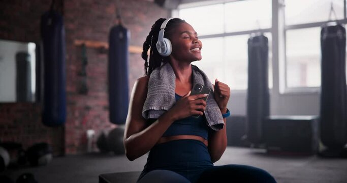 Woman, phone and headphones in gym for dancing, music or choice for internet radio at training. African person, smartphone or happy dancer with listening to audio streaming subscription on mobile app