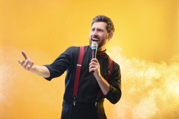 Emotional man with microphone singing on yellow background