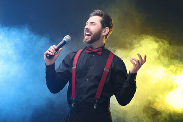 Emotional man with microphone singing in color lights