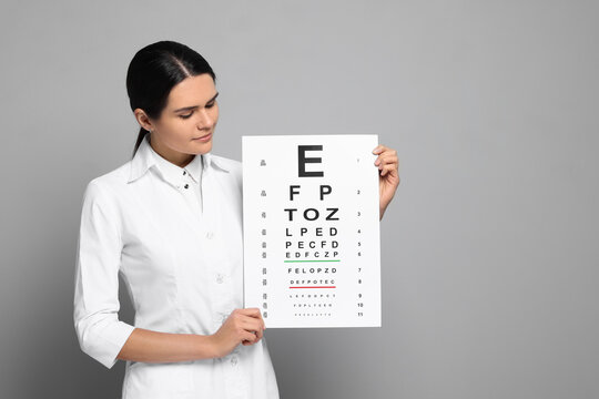 Ophthalmologist with vision test chart on gray background, space for text