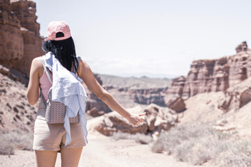 Naklejka premium girl in the canyon traveling through the canyon with a phone and a backpack in the summer at sunset