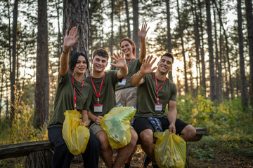 portrait of group of friends volunteers prepare to collect garbage waste and clean forest nature in...