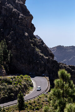 SPAIN, Canary Islands, Gran Canaria, Municipio Tejeda. Car on the road crossing the famous protected natural area of Roque Nublo (Rock in the Clouds), in the island of Gran Canaria